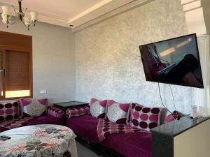 sala de estar con sofá y TV de pantalla plana en Villa avec piscine à louer aux environs de Birjdid 46km km de Casablanca route d'El Jadida, en Bir Jedíd Saint-Hubert