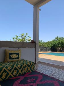 una cama sentada en un porche junto a una piscina en Villa avec piscine à louer aux environs de Birjdid 46km km de Casablanca route d'El Jadida, en Bir Jedíd Saint-Hubert