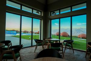 a room with tables and chairs and large windows at Hotel Qvevrebi in Tʼelavi