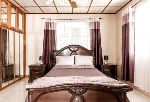 een slaapkamer met een bed met 2 nachtkastjes en een raam bij Joyful Ambiance Retreat 