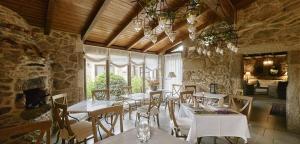 a restaurant with tables and chairs in a stone building at Hotel Rustico Lugar Do Cotariño in Camariñas