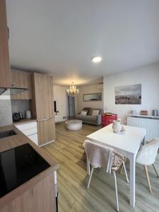 eine Küche und ein Wohnzimmer mit einem weißen Tisch und Stühlen in der Unterkunft Appartement cosy et lumineux proche Paris & Disney in Champigny-sur-Marne
