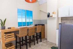 a kitchen with a bar with chairs and a window at Acogedor Loft, Playa Las Flores in La Libertad