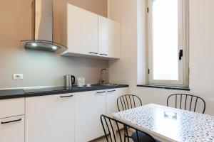 a kitchen with white cabinets and a table with chairs at Duomo - Citylife Pink Vintage APT center Milan in Milan