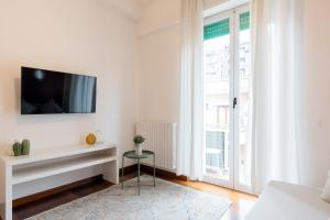 a white living room with a tv on a wall at Duomo - Citylife Pink Vintage APT center Milan in Milan