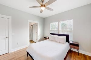 een witte slaapkamer met een bed en een plafondventilator bij The Primrose in Pensacola