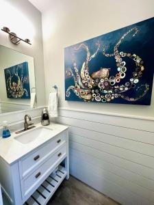 een badkamer met een wastafel en een octopus schilderij aan de muur bij "SEA ESTA"- Modern Coastal Style, Dog Friendly, Includes 6-person GOLF CART!! in Carolina Beach
