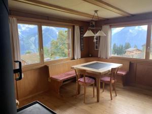 a dining room with a table and chairs and windows at Revier Silberdistel im Schwettiberg in Braunwald
