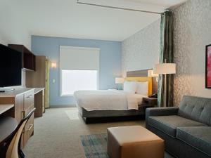 アトランタにあるHome2 Suites By Hilton Atlanta Airport College Parkのベッドとソファ付きのホテルルーム