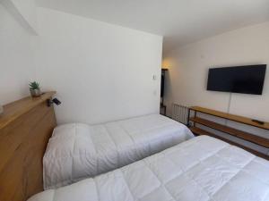 sypialnia z 2 łóżkami i telewizorem z płaskim ekranem w obiekcie Joli Apartments - Studio B - 2 pax en el corazón de la ciudad w mieście San Martín de los Andes