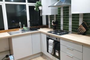 una cucina con armadi bianchi, lavandino e piano cottura di Opulent 4 bed house with parking a Manchester