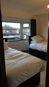 two beds in a room with a window at Opulent 4 bed house with parking in Manchester