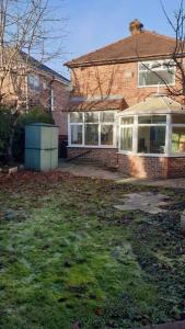 a brick house with a yard in front of it at Opulent 4 bed house with parking in Manchester