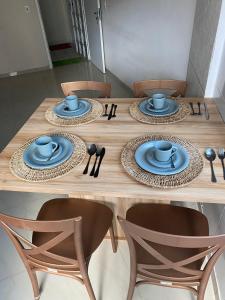 uma mesa de madeira com pratos azuis e utensílios em Quarto e Sala Beira Mar Maceió em Maceió