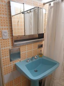 een badkamer met een blauwe wastafel en een spiegel bij FourDoor in Guaymallen