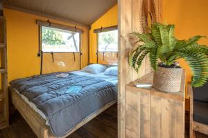 Camping L'Orangeraie في Cálig: غرفة نوم مع سرير وزرع الفخار