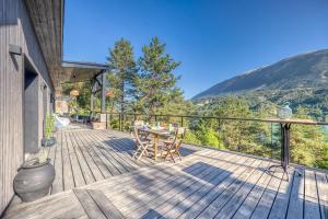 eine Holzterrasse mit einem Tisch und Stühlen darauf in der Unterkunft La Maison du Lac - Passerelles de Monteynard in Lavars