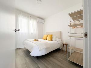 a white bedroom with a white bed with yellow pillows at Apartamentos Gredos 304 in Jaraiz de la Vera