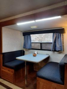 uma mesa e banco num pequeno quarto com uma janela em CASA RODANTE LUNA super cómoda y equipada em San Pedro Atlapulco
