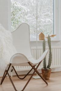 einen weißen Stuhl in einem Zimmer mit Kaktus in der Unterkunft Design Holiday Home in Ermelo