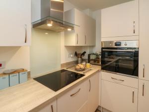 a kitchen with white cabinets and a black counter top at Harley's Hideaway in Appledore +15 photos