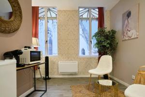 sala de estar con escritorio, TV y ventanas en NG SuiteHome - Lille I Roubaix Centre I Grand Place - Balnéo - Netflix - Wifi, en Roubaix
