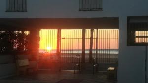 una puesta de sol vista a través de las puertas de una casa en Dúplex 4, primera línea de Playa, en Sanlúcar de Barrameda