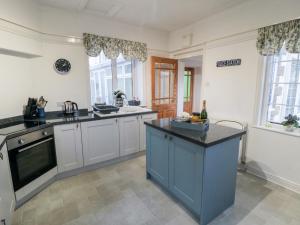 a kitchen with white cabinets and a blue island at The Old Police House in Saltburn-by-the-Sea