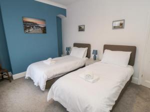2 Betten in einem Zimmer mit weißer Bettwäsche in der Unterkunft The Old Police House in Saltburn-by-the-Sea