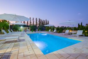 - une piscine avec des chaises et des parasols blancs dans l'établissement Villa VentoSolare Luxury - Specchia, à Specchia