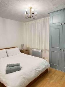 a bedroom with a large white bed and a chandelier at Cosy 1 Bed, Wembley in London