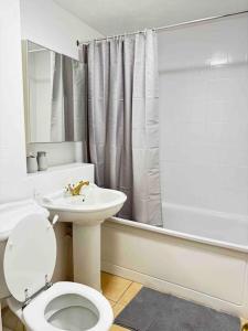 a white bathroom with a toilet and a sink at Cosy 1 Bed, Wembley in London
