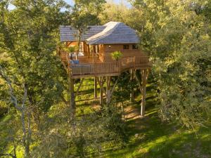 a tree house with a deck in the trees at Cabane de Prestige avec Jacuzzi et Sauna privatifs in Alzonne