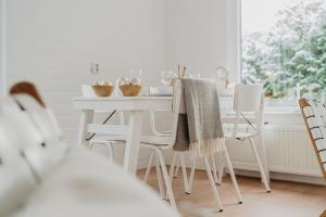 ein weißes Esszimmer mit einem weißen Tisch und Stühlen in der Unterkunft Design Holiday Home in Ermelo