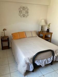 a bed in a room with two tables and a lamp at Betty's Beach Condominium in Playas