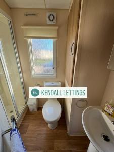 a small bathroom with a toilet and a sink at Tebay (Green Lawns) in Selsey
