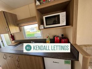 a kitchen with a microwave and a counter top at Tebay (Green Lawns) in Selsey