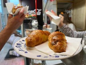 a person holding up a plate with two croissants at New Generation Hostel Belgrade Center in Belgrade
