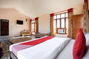 a bedroom with a large white bed with red pillows at Flagship Corbett Farm Homestay in Rāmnagar