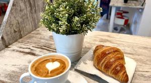 a cup of coffee and a croissant on a table at NEW GENERATION HOSTEL Prague center in Prague +33 photos