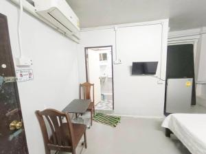 Cette petite chambre blanche dispose d'une table et d'un réfrigérateur. dans l'établissement ห้องพักสุขสบายวังหลัง, à Bangkok