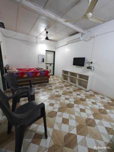 a room with a chair and a bed and a television at Kulswami Cottage Alibaug in Alibaug