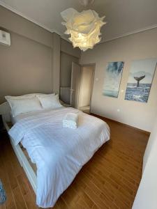 una camera da letto con un grande letto bianco e un lampadario a braccio di Sea view penthouse with huge terrace ad Atene