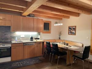 uma cozinha com armários de madeira e uma mesa com cadeiras em Chalet Sträba em Bellwald