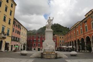 una estatua en medio de una ciudad con edificios en La Porta sui Monti di Luna, en Carrara