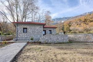 a stone house with a stone wall in a yard at Villa Ntora in Xylopároikon
