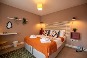 a bedroom with a large bed with orange sheets at Minchin House, King beds workspace corporates parking sleeps 8 in Dallington