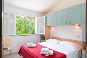 a bedroom with a bed with a red blanket and a window at Golfo di Maremma Village in Albinia