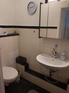 een badkamer met een wastafel, een toilet en een klok bij Schlossblick keine Montagewohnung 