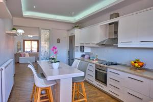 cocina con armarios blancos, mesa y sillas en Elena Luxury Suite Agios Stefanos, en Agios Stefanos